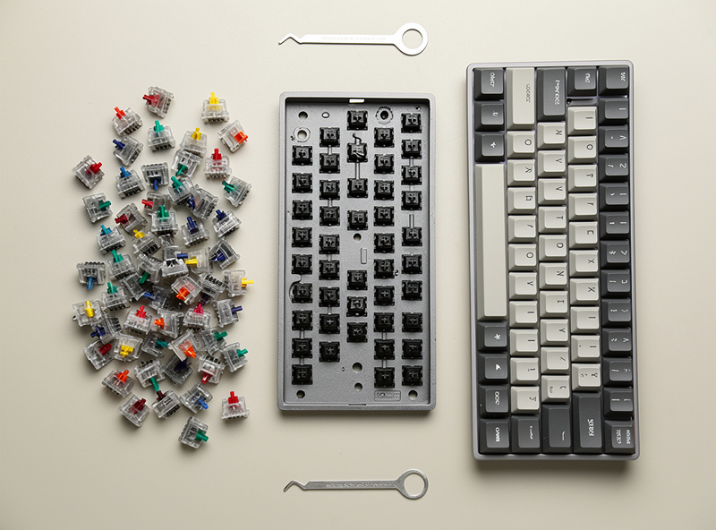 A budget keyboard parts list laid out on a desk: hotswap board, switch 90-pack, PBT keycaps, and a switch puller