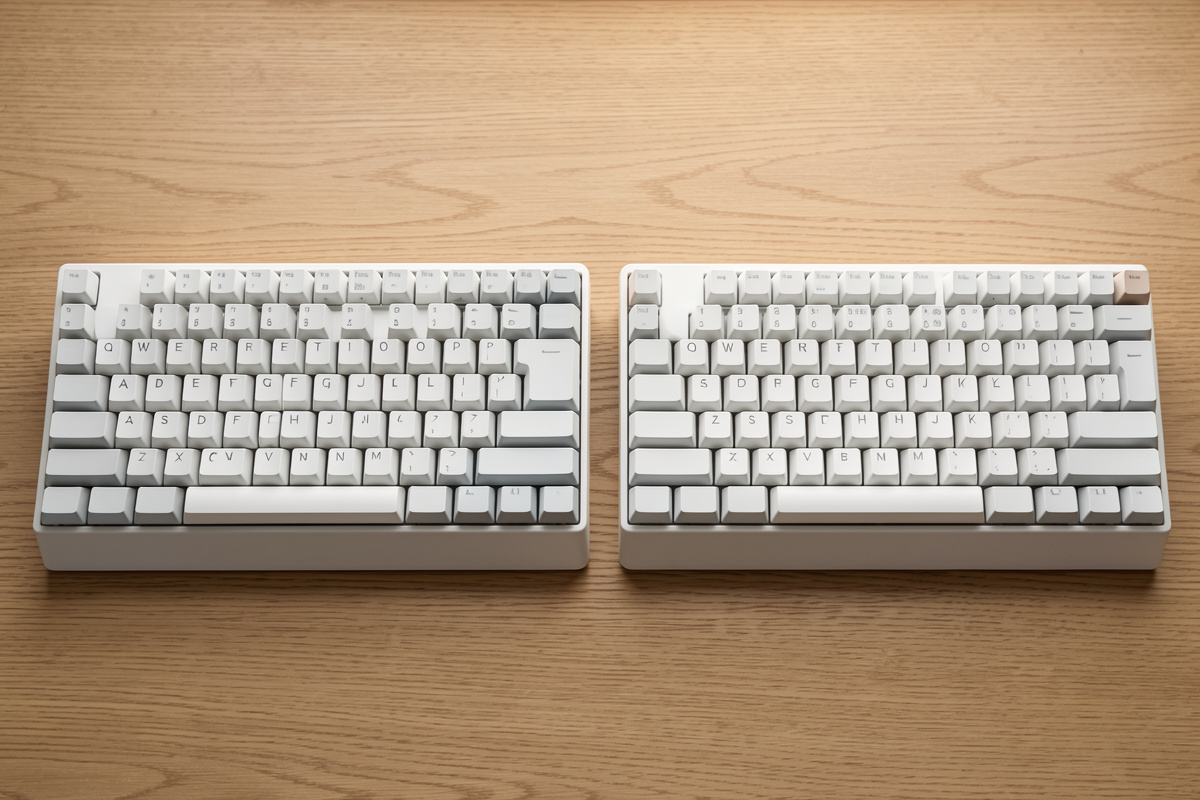 Two keyboards side by side, one with factory-lubed switches and one hand-tuned, on a desk