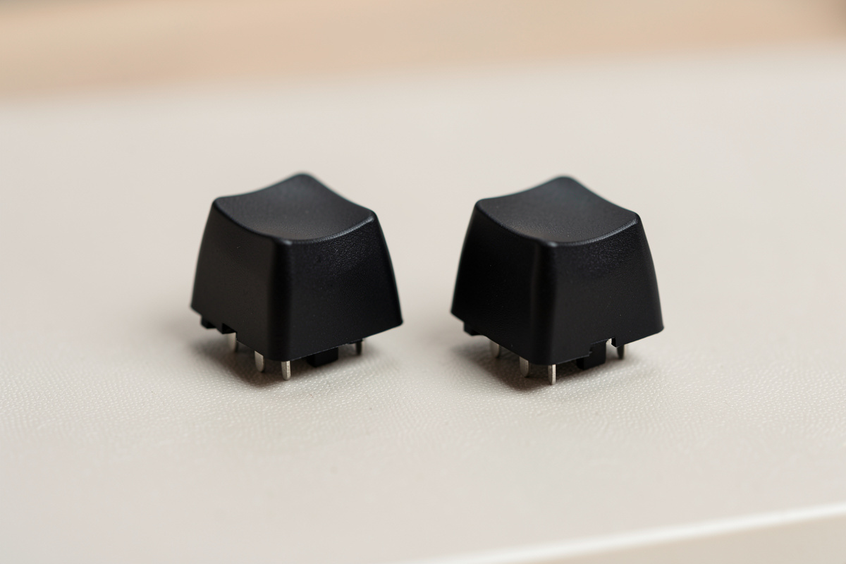 Two identical keyboard switches side by side, one stock and one lubed, on a desk mat