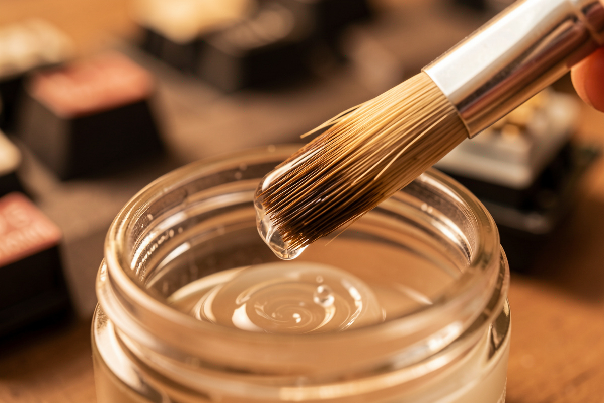 A brush taking a small amount of grease from a jar, ready to apply to a switch stem