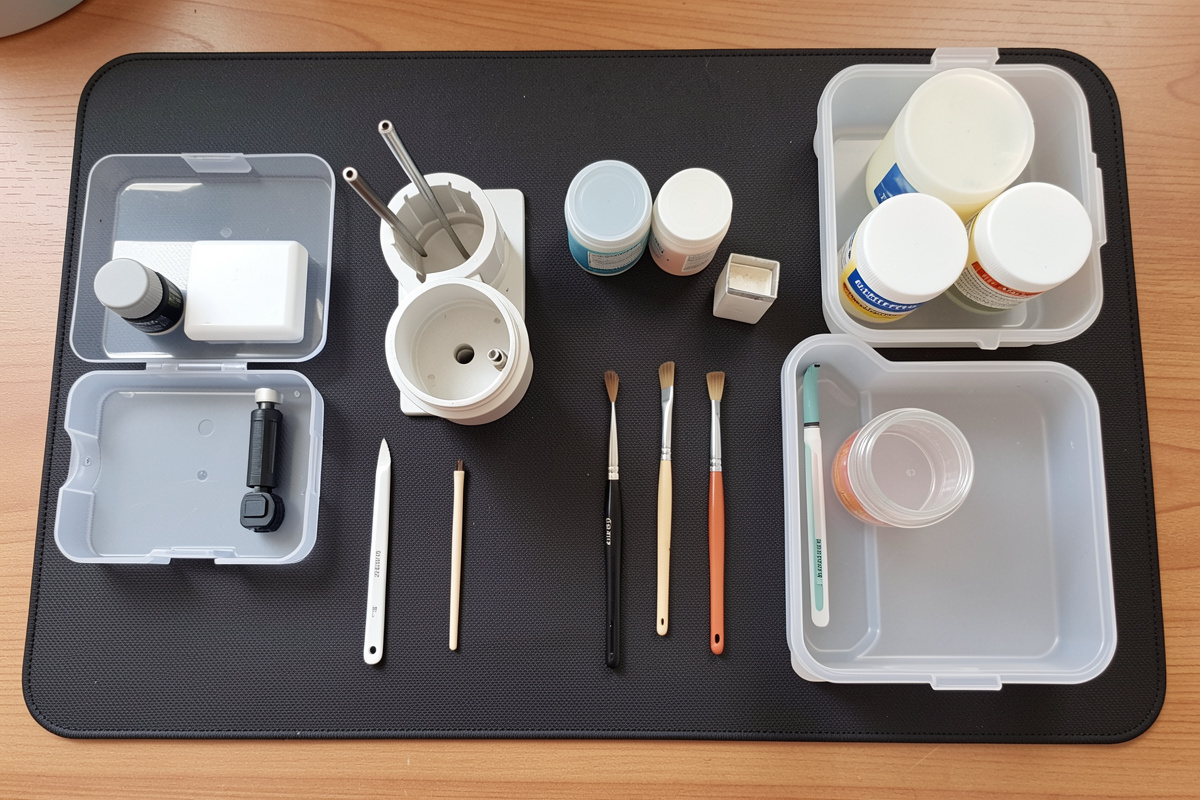 A keyboard switch lube station laid out with opener, stem holder, brushes, lube jars and sectioned trays