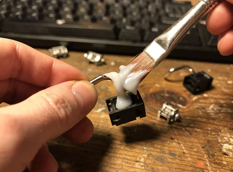 Applying thick dielectric grease to a keyboard stabilizer wire end with a small brush