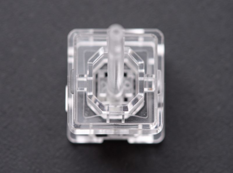 Transparent keyboard switch housing showing the long center pole inside