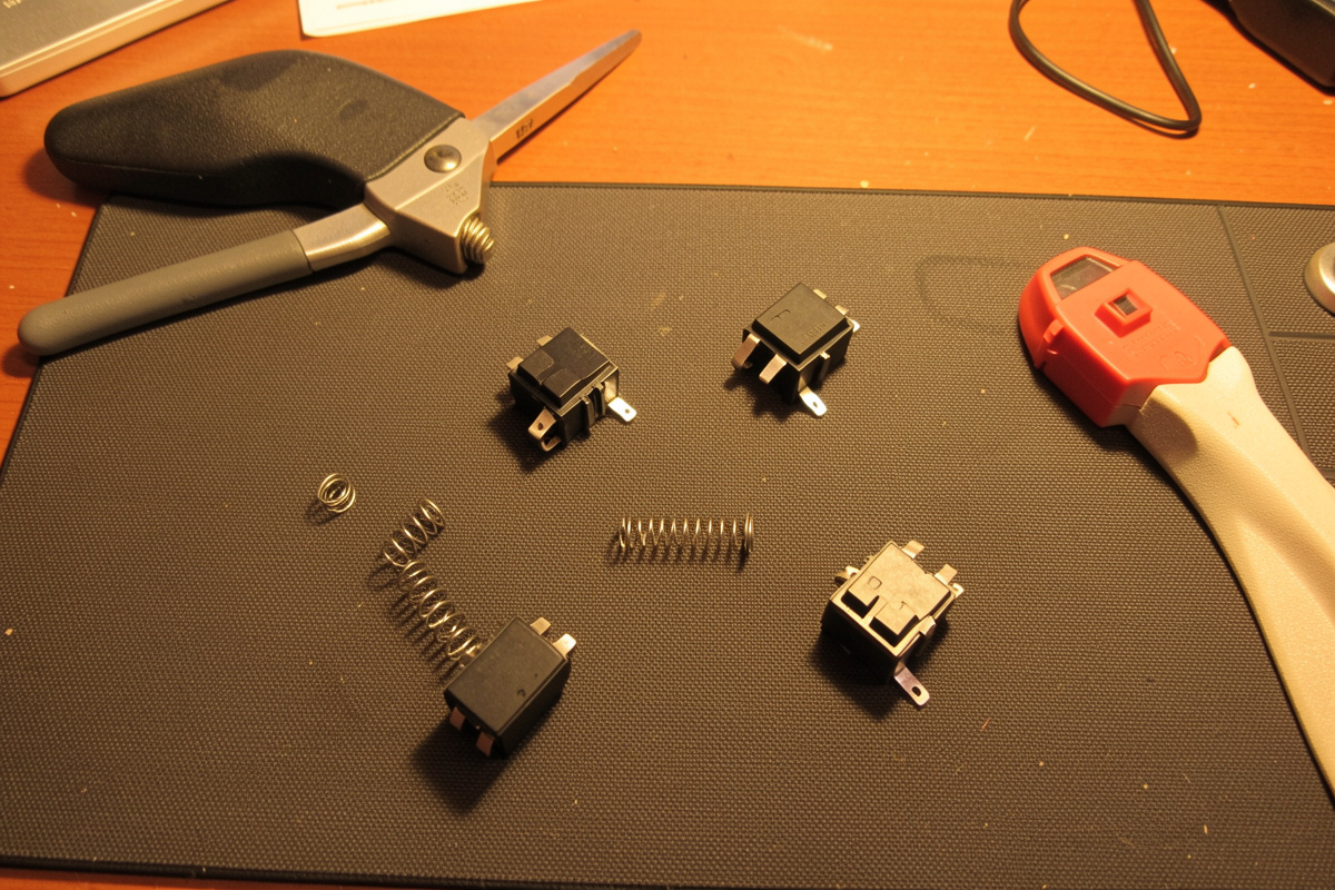 A switch opener tool next to disassembled switches with springs removed for swapping