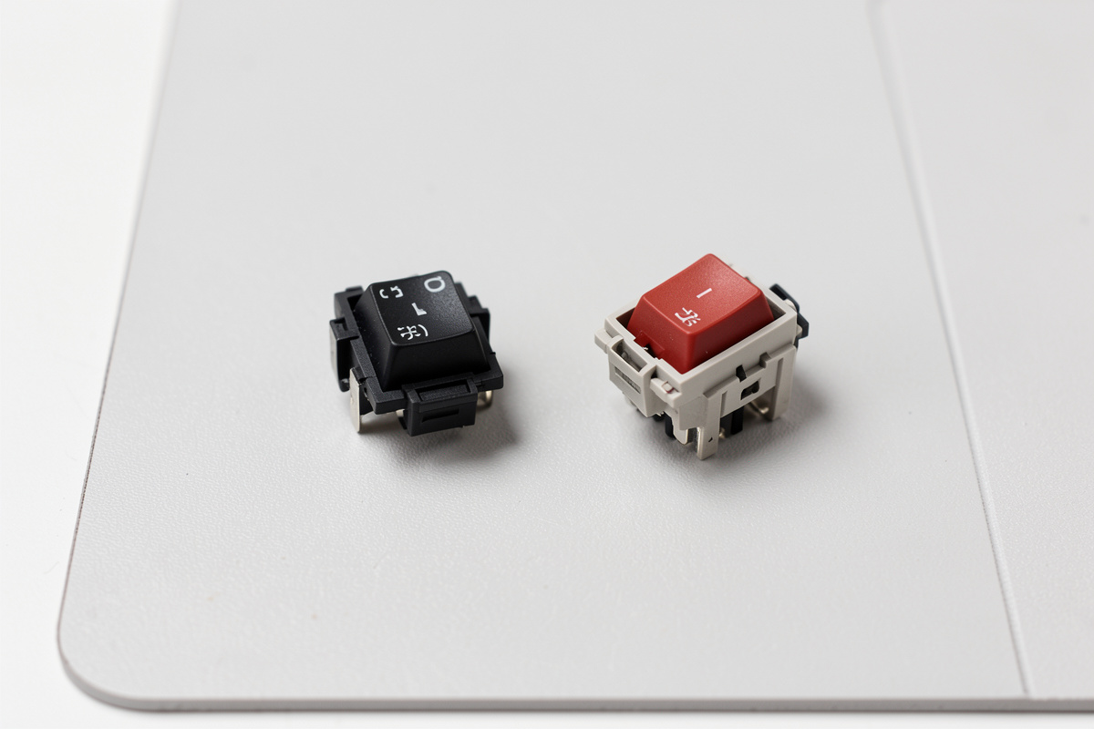 A keyboard switch reassembled with a film fitted, sitting next to an unfilmed switch for comparison